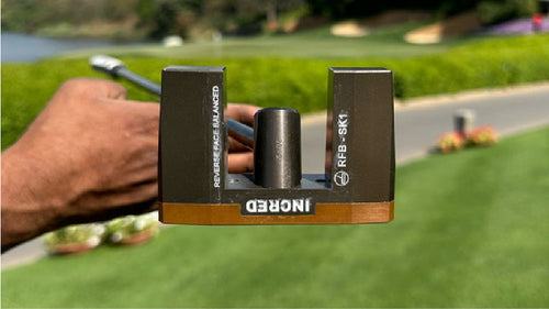 RFB SK1 putter held face-down on a golf course, showing the RFB-SK1 engraving